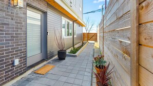 En smal udendørs sti med et træhegn, en murstensmur og en moderne bygning med en garageport.