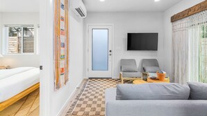 En moderne stue med sofa, to lænestole, et fjernsyn og et mønstret tæppe.