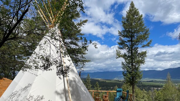 A white teepee on a wooden deck with a view of mountains and trees. - Mountain Quest Tipi (Rexford)