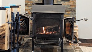 A stone fireplace with a black chimney, a framed welcome sign, and a fire burning inside.