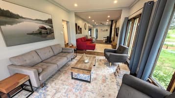 Un salon spacieux avec une grande fenêtre, un canapé rouge, un canapé gris et une table basse.