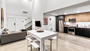 A modern kitchen with a white table, grey sofa, and stainless steel appliances. - Urban Loft in Redmond Core (Redmond)