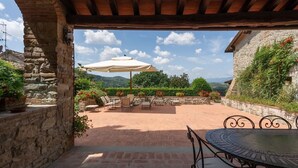 An outdoor patio with stone flooring, a round table, and several chairs. - Villa Nocella - Private villa with pool in Tuscany (Dicomano)