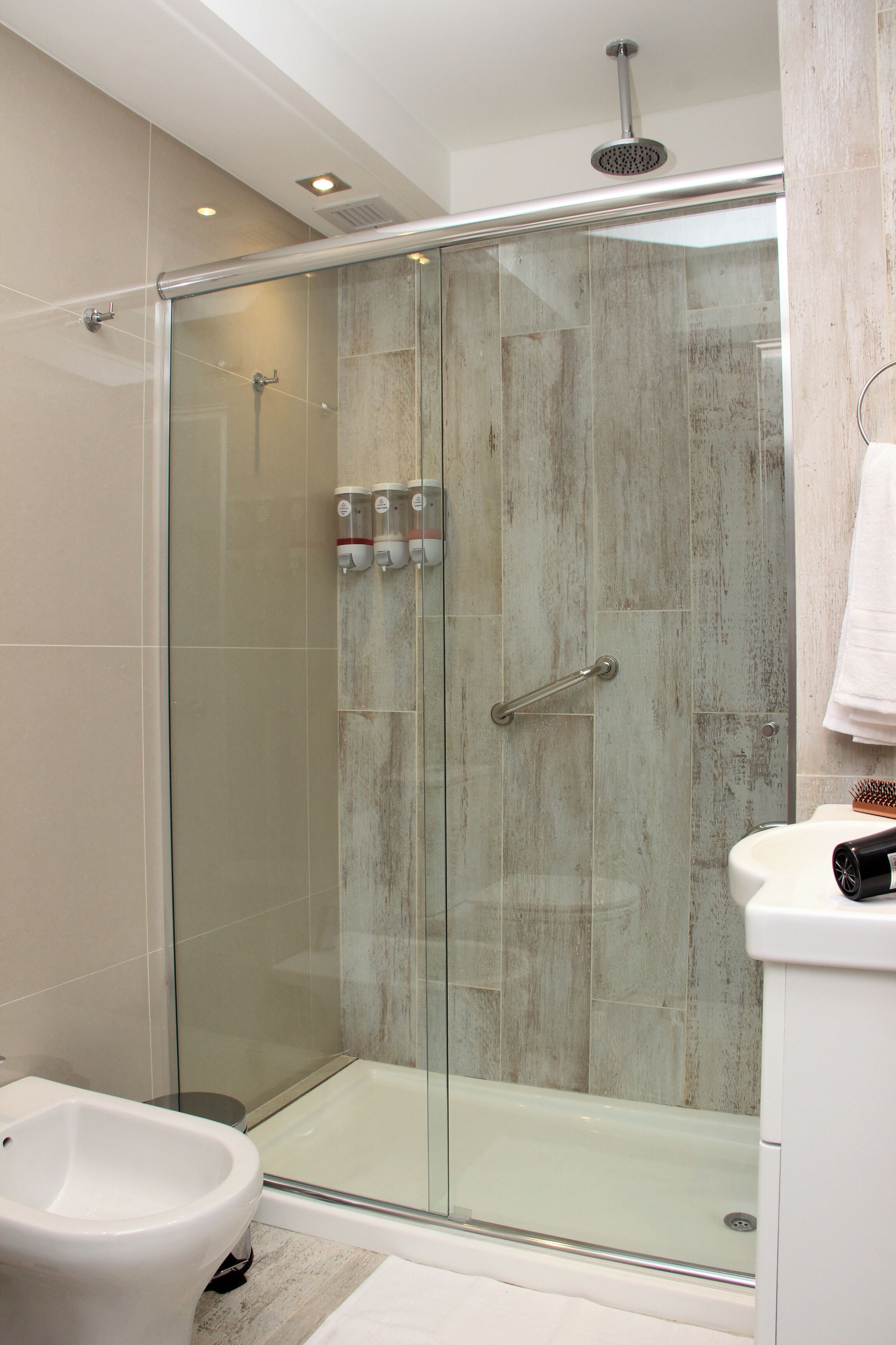Ein modernes Badezimmer mit einer gläsernen Duschkabine, einem weißen Waschbecken und einem Bidet.
