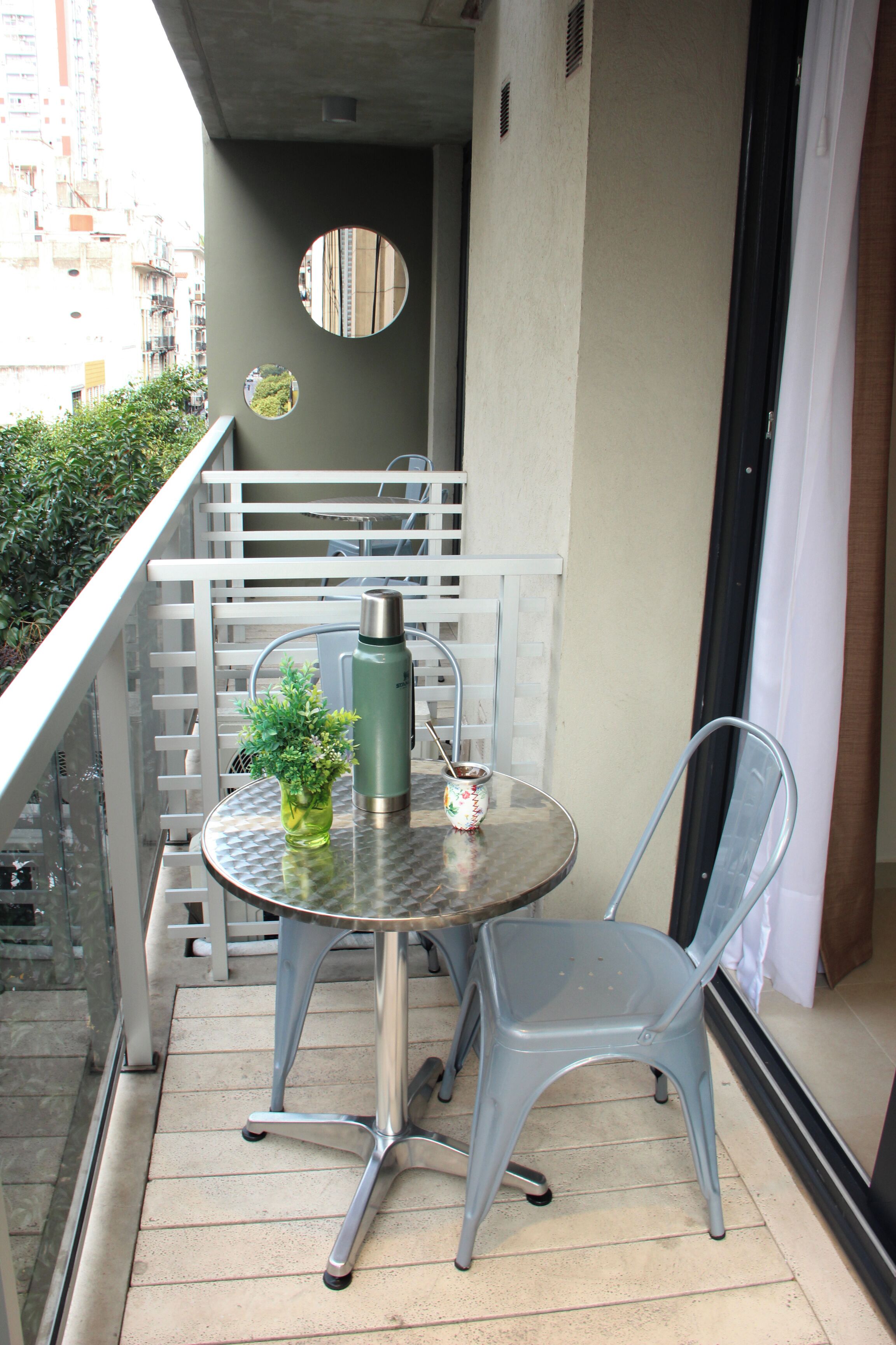 A small balcony with a table, chair, and a potted plant.