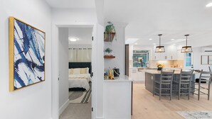 A modern apartment with a kitchen, dining area, and a bedroom.