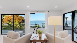 A modern living room with a view of the sea, a tripod, and a lamp.