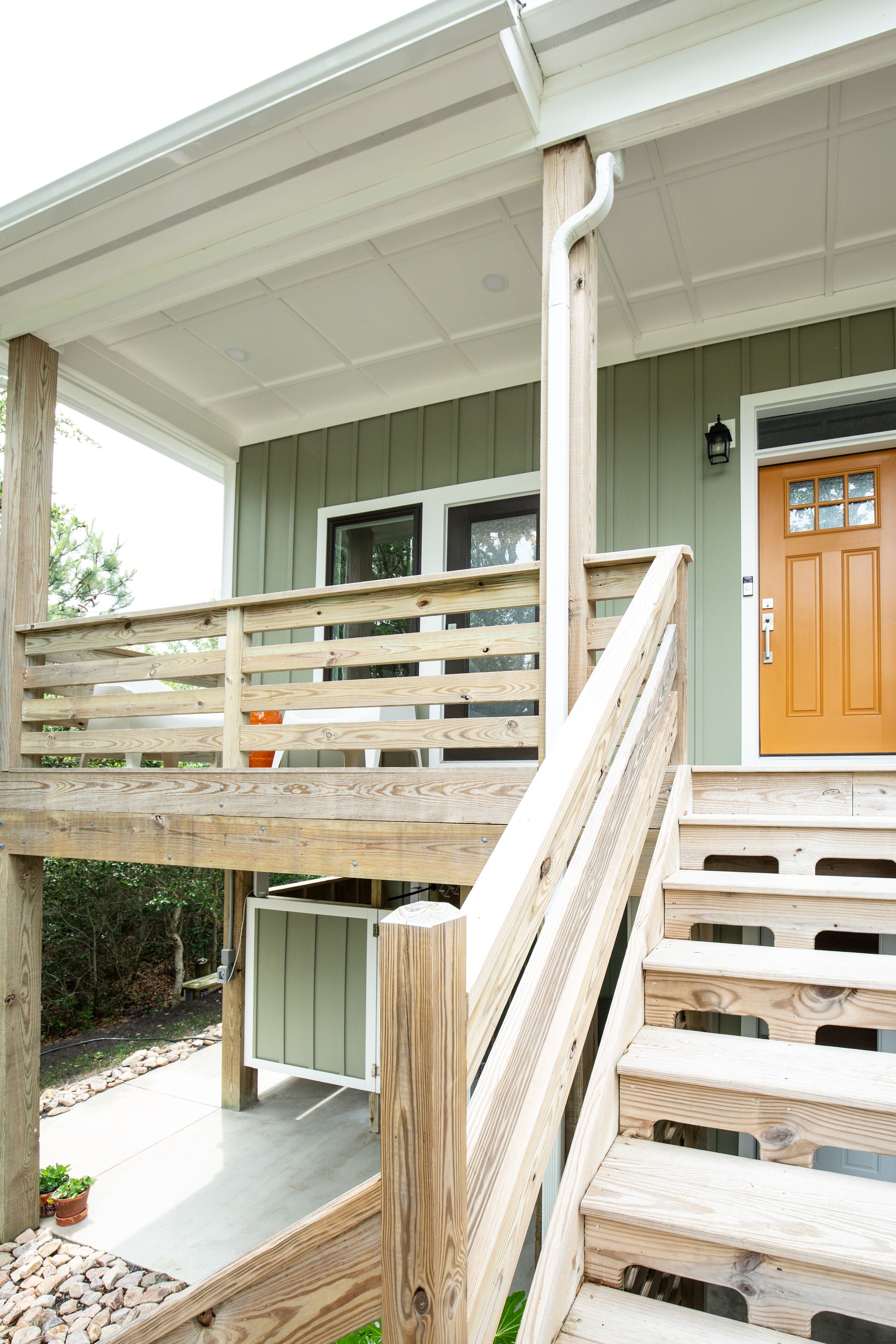 A wooden staircase leading to a porch with a green door and a window.