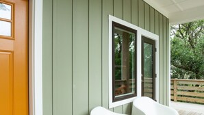 A porch with a wooden floor, a green wall, and a white door. - Modern Soundfront Studio, Pier access, Sunsets, Fishing, Watersports, Beach (Salvo)