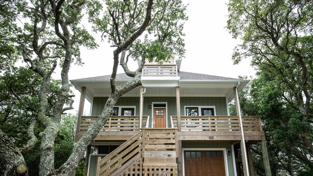 A two-story house with a wooden deck and a front garage. - Modern Soundfront Studio, Pier access, Sunsets, Fishing, Watersports, Beach (Salvo)