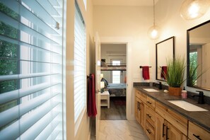A modern bathroom with a large mirror, two sinks, and a wooden vanity.