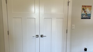 A closed white door with a handle, a wall-mounted electrical outlet, and a poster on the wall. - Modern Soundfront Studio, Pier access, Sunsets, Fishing, Watersports, Beach (Salvo)