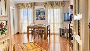 A dining area with a wooden table and chairs, a rug, and a painting on the wall.