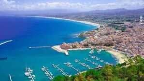 A coastal town with a marina, buildings, and a beach.