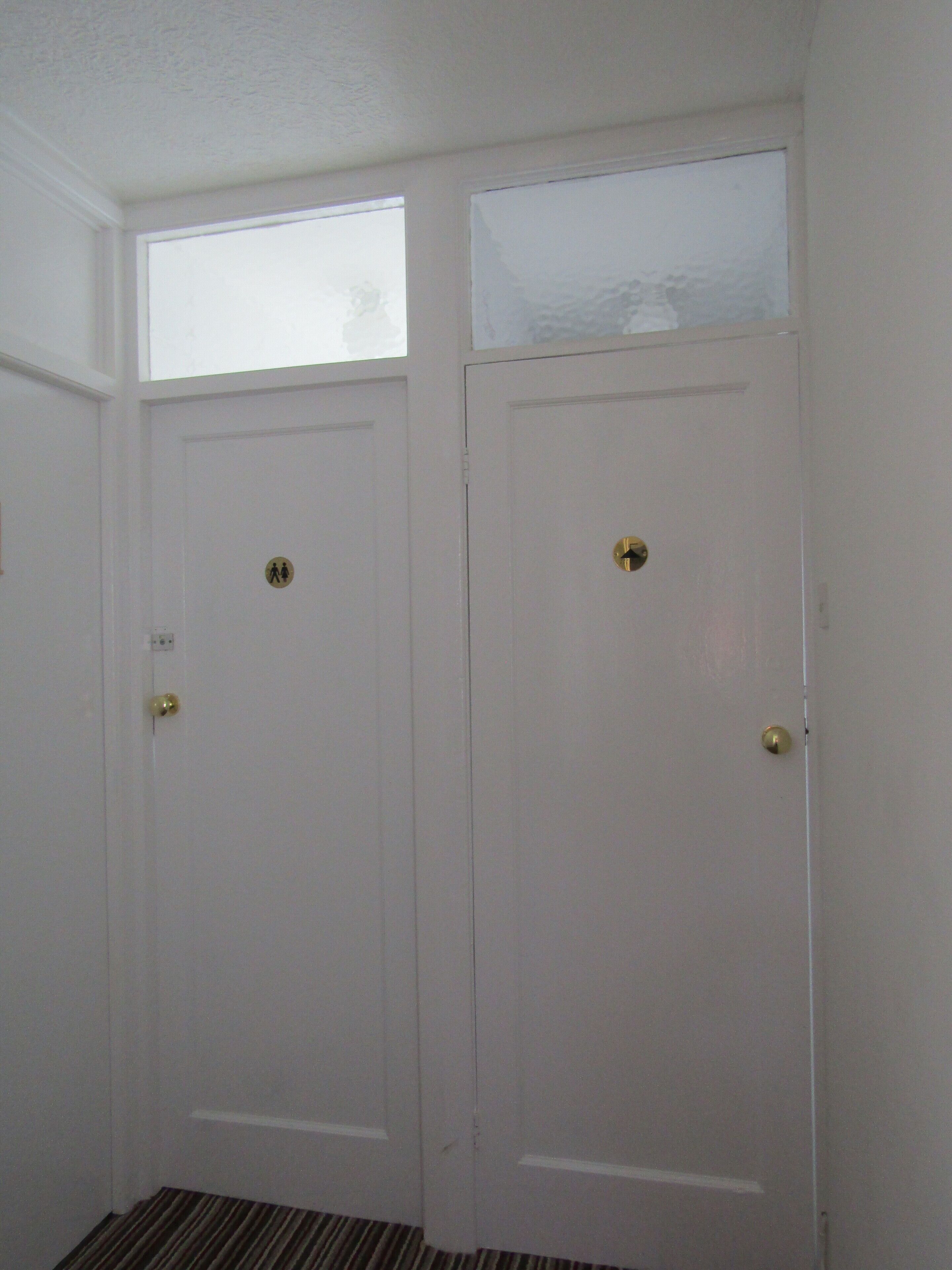 Two white doors with brass handles and a small window above each.