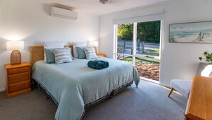 Una camera da letto con un letto, comodini, una lampada, una finestra con vista e un quadro appeso al muro.