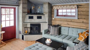 A cozy log cabin interior with a fireplace, a sofa, and a table. - Cozy home in Reinli with sauna (Reinli)