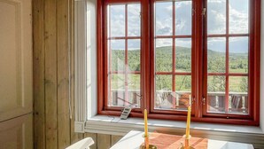 A room with a large window offering a view of a green landscape and hills. - Cozy home in Reinli with sauna (Reinli)