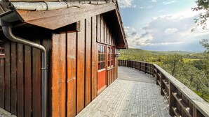 A wooden cabin with a wooden deck and a view of a mountainous landscape. - Cozy home in Reinli with sauna (Reinli)