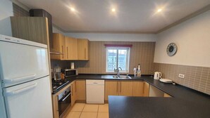 A compact kitchen with a Bosch refrigerator, a microwave, a dishwasher, and a sink.