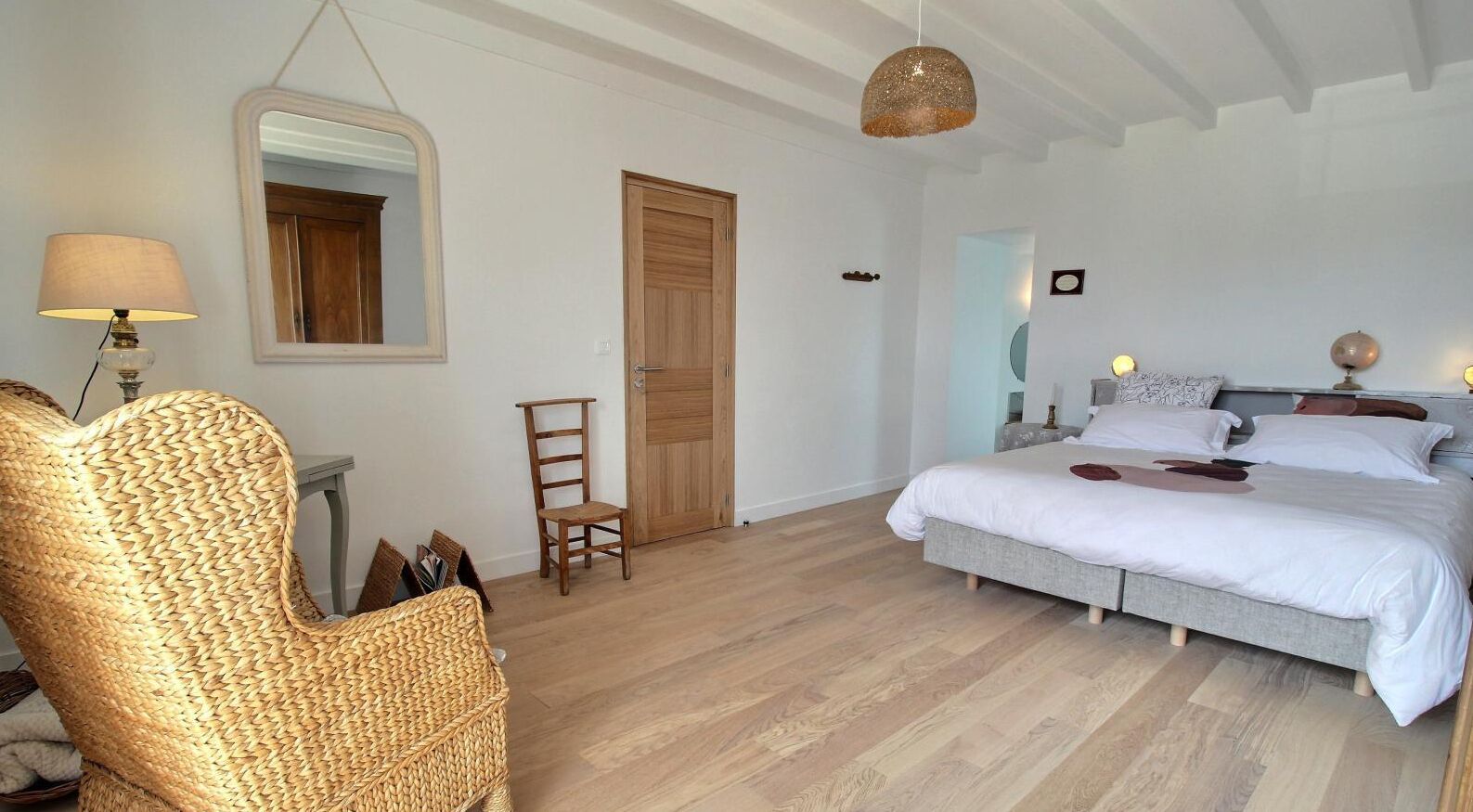 A bedroom with a bed, a chair, a lamp, and a door.