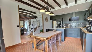 Una cucina moderna con un tavolo da pranzo in legno, sedie trasparenti e un pavimento in piastrelle a spina di pesce.