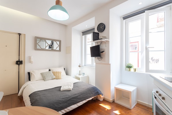 Une chambre moderne avec un lit, une table de chevet, une télévision et une fenêtre donnant sur un beau paysage.