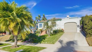 A residential property with a well-maintained lawn, palm trees, and a garage. - Cozy Beach Studio – Sleeps 2, Walk to Ocean (San Diego)