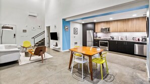 A modern kitchen with stainless steel appliances, a dining area with a wooden table and chairs, and a staircase leading to another level. - Posh Lofty Pad in Central Redmond (Redmond)