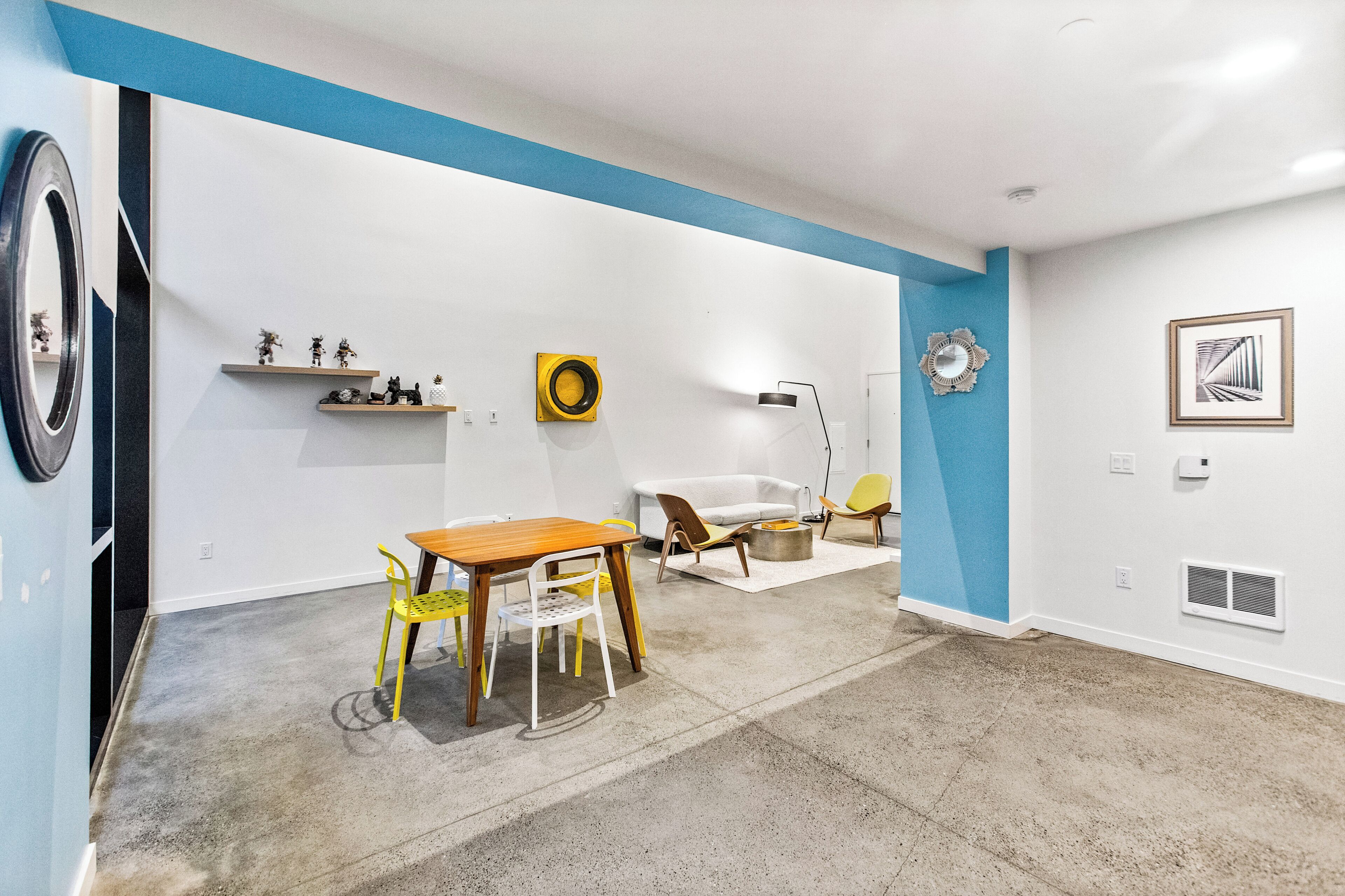 A modern living room with a dining area, featuring a round table, chairs, and a sofa.