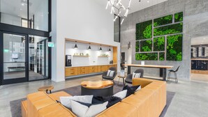 A modern lobby with a reception desk, seating area, and a large green wall. - Posh Lofty Pad in Central Redmond (Redmond)