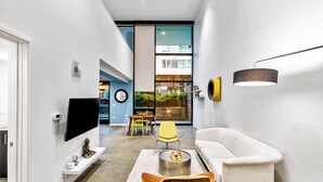 A modern living room with a sofa, chairs, a coffee table, and a TV mounted on the wall. - Posh Lofty Pad in Central Redmond (Redmond)
