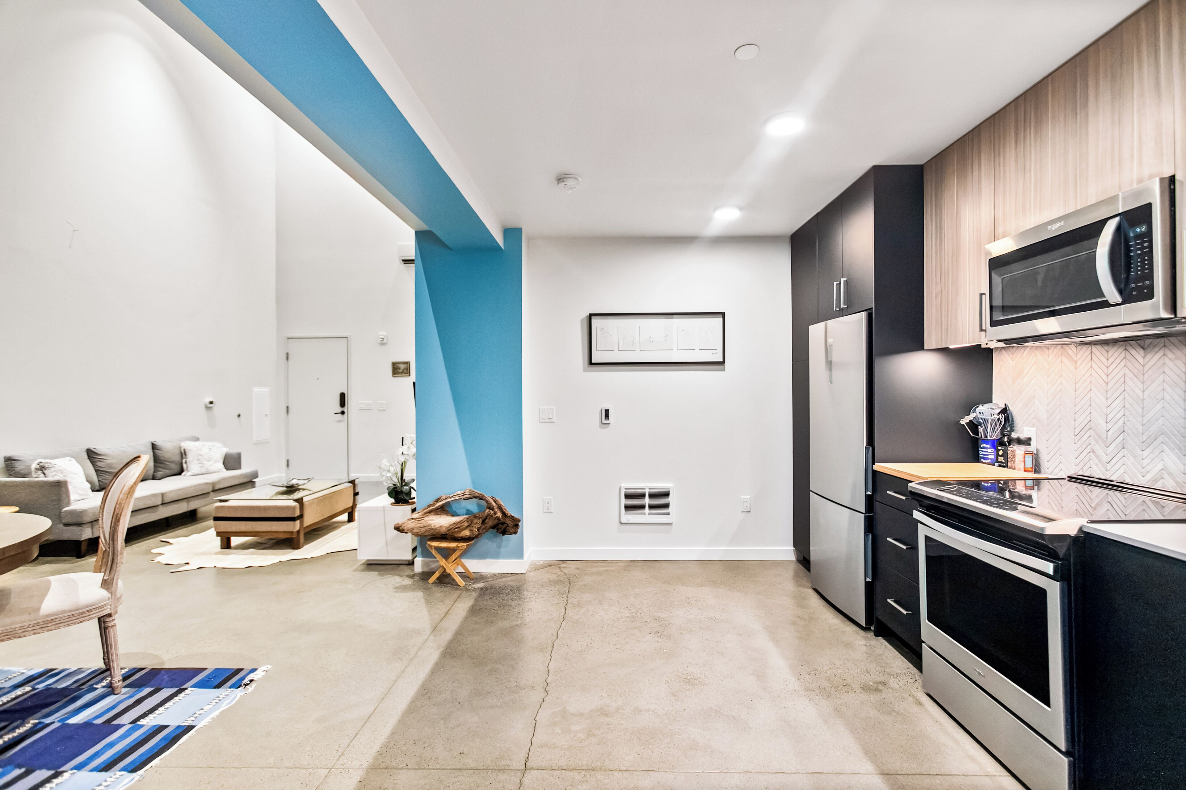 Een moderne keuken met een magnetron, oven en koelkast. Er is een eethoek met een tafel en stoelen.
