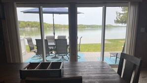 A dining area with a view of a lake, outdoor furniture, and a table with a fruit drink box. - Torch Lake Sandbar Escape (Rapid City)