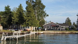 A lakeside property with a dock, a covered patio, and a house with a red star on the roof. - Torch Lake Sandbar Escape (Rapid City)