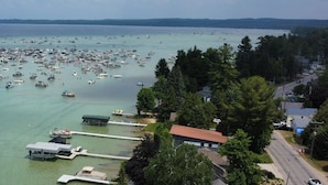 An aerial view of a marina with numerous boats docked, surrounded by residential buildings and dense greenery. - Torch Lake Sandbar Escape (Rapid City)