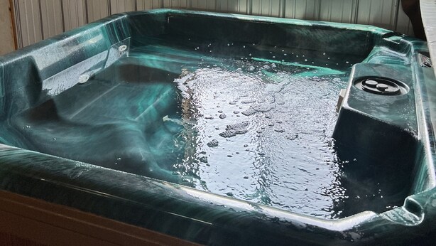 Ett bubbelbad i en stuga av trä med ett fönster som vetter ut mot en innergård.