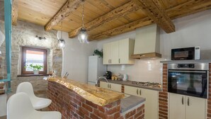 A kitchen with a brick island, white cabinets, a microwave, and an oven. - Beautiful home in Buje (Buje)