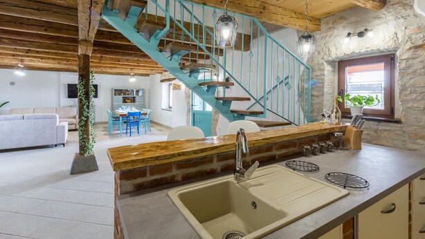 A kitchen with a sink, a wooden countertop, and a blue staircase. - Beautiful home in Buje (Buje)
