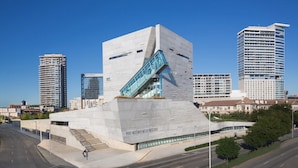 Ein modernes Gebäude mit einem markanten, ungewöhnlichen Winkeldesign, das eine imposante Treppe und eine Glasfassade zeigt.