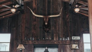 A rustic interior with wooden beams, a large horned animal head, and a fireplace. - Paso Robles Ultimate Farm Stay! Country Oasis!! Very Unique!!! (San Miguel)
