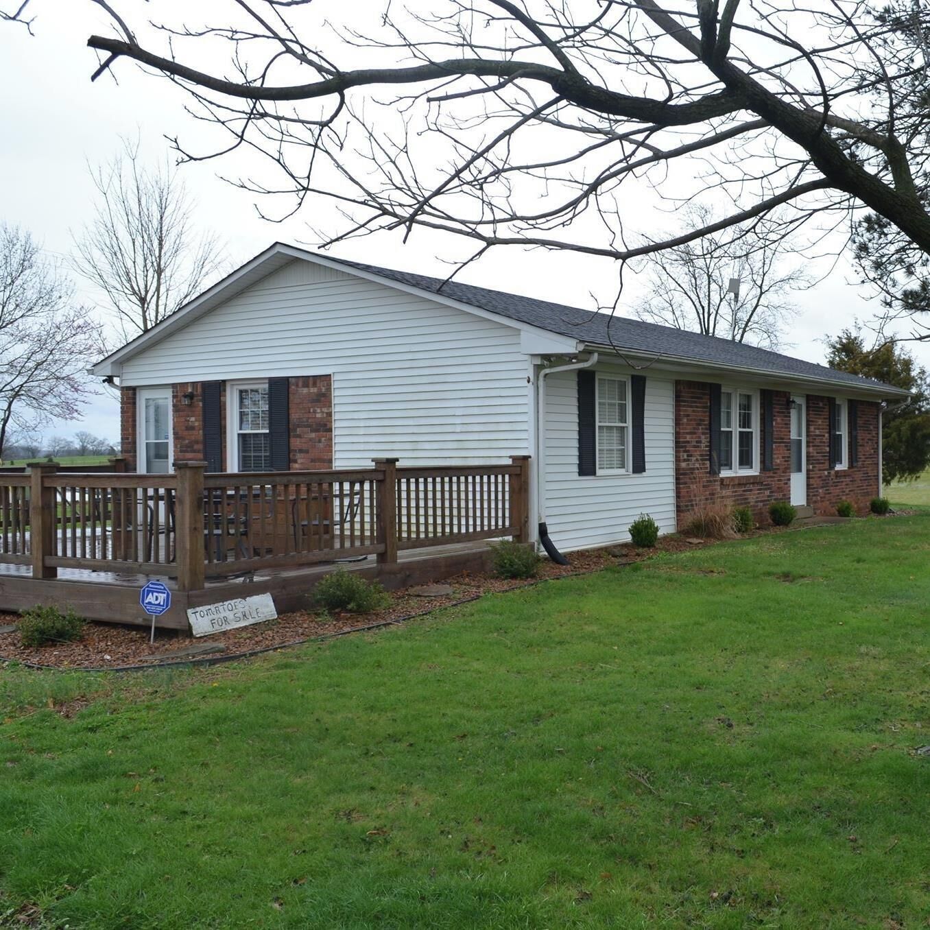 A single-story house with a front porch, a brick section on the left, and a wooden fence.