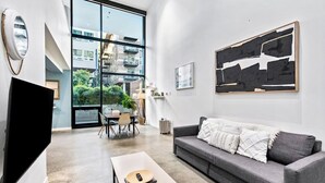 A modern living room with a grey sofa, a flat-screen TV, and a large abstract painting. - Open Loft in Redmond Core - 92 Walkscore (Redmond)