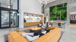 A modern lobby with a reception desk, seating area, and a large green wall. - Open Loft in Redmond Core - 92 Walkscore (Redmond)