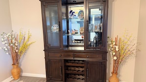 A dark wooden cabinet with glass doors, two wicker vases with dried flowers, and a wine rack. - South County ranch house walking distance to Grant Trail (St. Louis)