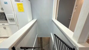 A staircase with a handrail, a door at the top, and a refrigerator with a 'No Smoking' sign. - South County ranch house walking distance to Grant Trail (St. Louis)