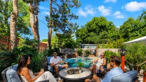 A group of people seated around a circular outdoor table with a pool in the background. - 9 BR Modern Ranch House with Beach House Resort (Las Vegas)