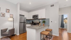 A modern kitchen with white cabinets, stainless steel appliances, and a granite countertop.