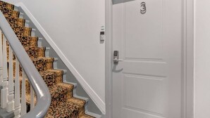 A staircase with patterned carpet leading to a white door marked with the number 3.