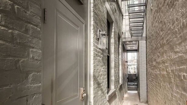 A narrow hallway with brick walls and a white door.